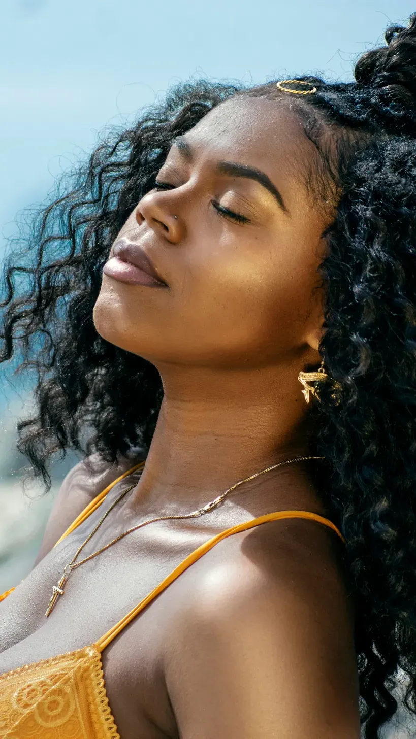 Black woman in golden light, eyes closed, face turned to the sun